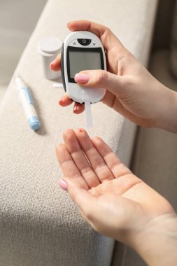 Diyabet. Kan şekeri seviyesini glukometreyle ölçen kadın, yakın plan.
