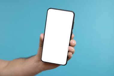 Açık mavi arka planda akıllı telefon gösteren bir adam, yakın plan. Tasarım için model