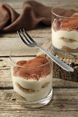 Lezzetli tiramisu, gözlük ve çatal, ahşap masa.