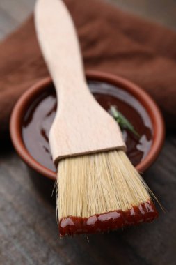 Marinade in bowl and basting brush on table, closeup clipart