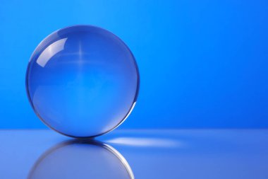 Mavi arka planda ayna yüzeyinde şeffaf cam top. Metin için boşluk