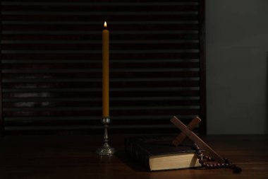 Kilise mumu, İncil, haç ve ahşap masada tespih.