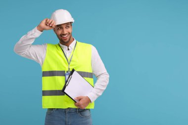 Açık mavi arkaplan üzerinde pano tutan sabit başlıklı mühendis, metin için boşluk