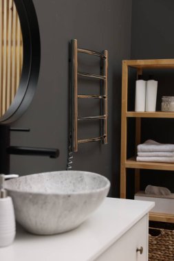 Isıtılmış havlu parmaklıkları ve modern mobilyaları olan şık bir banyo.