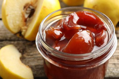 Kavanozda ev yapımı ayva reçeli ve ahşap masada meyveler, yakın plan.