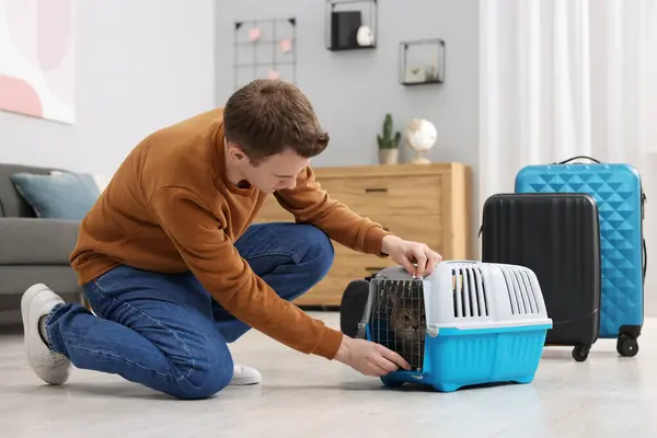 Travel with pet. Man closing carrier with cat at home
