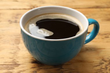 Ahşap masada bir fincan aromatik kahve, yakın plan.