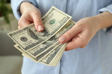 Para değişimi. Bulanık arka planda dolar banknotları sayan kadın, yakın plan
