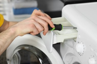 Tornavidalı tesisatçı, çamaşır makinesini içeride tamir ediyor, yakın plan.