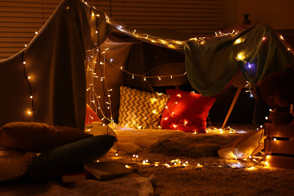 Beautiful play tent decorated with festive lights at home