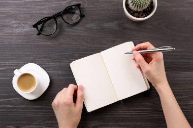 Gri ahşap masada defter ve kalemle oturan kadın. Metin için boşluk