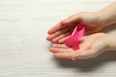 Göğüs kanseri farkındalığı. Beyaz ahşap masadaki pembe kurdeleli kadın, üst manzara. Metin için boşluk