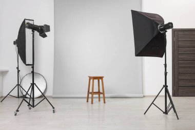 Fotoğraf stüdyosunda profesyonel ışıklandırma ekipmanlarıyla çevrili boş tabure.