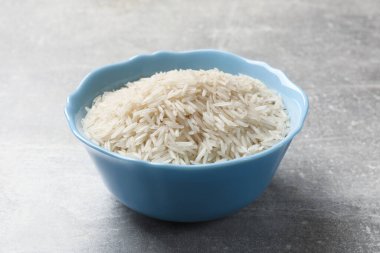 Tabakta çiğ basmati pilavı, gri masada, yakın plan.