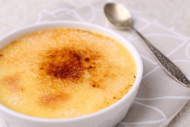 Lezzetli creme brulee kasede ve kaşıkta masada, yakın plan
