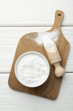 Kabın içinde kabartma tozu ve beyaz ahşap masa üzerinde kepçe, üst görünüm