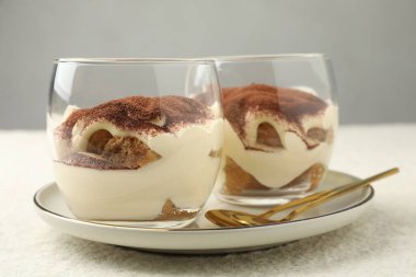 Lezzetli tiramisu bardaklar ve kaşıklar beyaz masada, yakın plan.