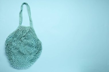 Açık mavi arka planda turkuaz ağ çanta, üst manzara. Metin için boşluk
