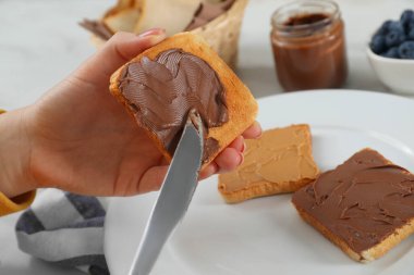 Masadaki tostun üzerine fıstık ezmesi döken kadın, yakın plan.