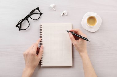 Beyaz ahşap masada defter ve kalemle oturan kadın. Metin için boşluk