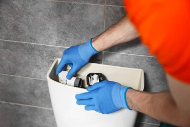 Su dolabındaki klozeti tamir eden tesisatçı, yakın plan.