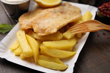 Tahta masada servis edilen lezzetli balık ve patates kızartması, yakın plan.