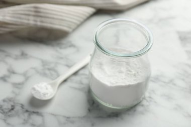 Kavanozda kabartma tozu ve beyaz mermer masada kaşık, yakın plan. Metin için boşluk