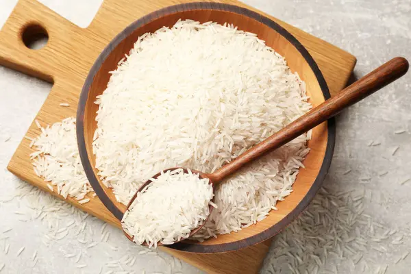 Tabakta çiğ basmati pilavı ve gri masada kaşık, üst manzara.