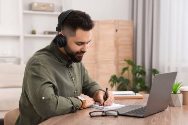 E-öğrenme. Genç adam çevrimiçi derste notlar alıyor.