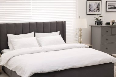 Şık bir yatak odası. Büyük yatağı, çekmeceleri ve lambası var.