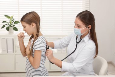 Hastanede öksüren kızı muayene eden doktor. Soğuk belirtileri