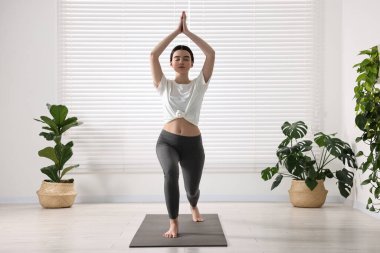 Yoga stüdyosunda hasırda hilal asana pratiği yapan bir kız. Yüksek atlama pozisyonu