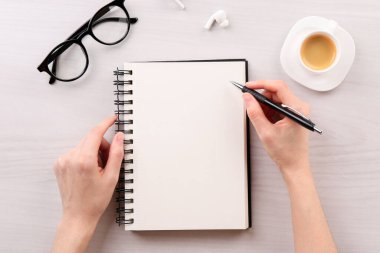 Beyaz ahşap masada defter ve kalemle oturan kadın. Metin için boşluk