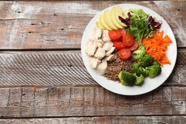 Dengeli beslenme ve sağlıklı yiyecekler. Tabakta farklı lezzetli ürünler var, ahşap masa, üst manzara. Metin için boşluk