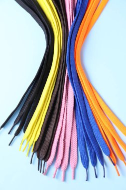 Açık mavi arkaplanda bir sürü renkli ayakkabı bağcığı var.