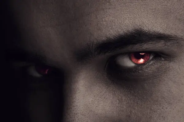 Evil eye. Man with red demonic eyes, closeup