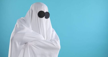 Ürkütücü hayalet. Açık mavi arkaplan üzerine beyaz sayfa ile kaplı kişi, metin için boşluk