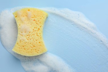 Açık mavi arka planda köpüklü sarı sünger, üst görünüm
