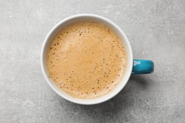 Açık gri masada bir fincan aromatik kahve, üst manzara.