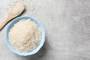 Tabakta çiğ basmati pilavı ve gri masada kaşık, üst manzara. Metin için boşluk