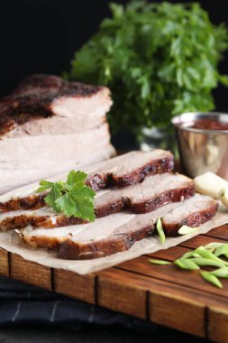 Kurutulmuş domuz eti parçaları soslu ve maydanozlu siyah desenli masa, yakın plan.