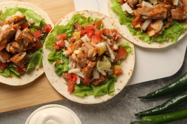 Sebzeli lezzetli tacolar ve gri desenli masa üzerinde et.