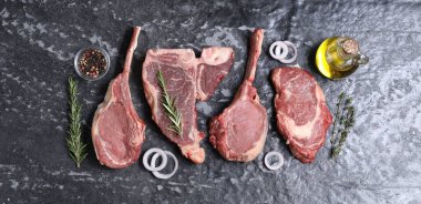 Taze çiğ et ve gri desenli masada farklı baharatlar.