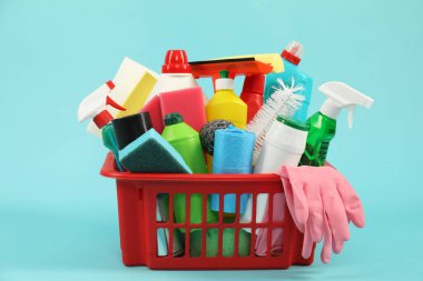 Açık mavi arka planda plastik sepette farklı temizlik ürünleri
