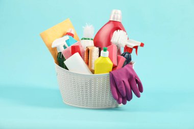 Açık mavi arka planda sepette farklı temizlik ürünleri