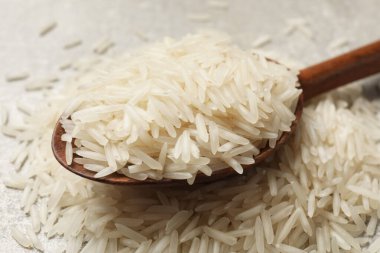 Çiğ basmati pilavı ve ahşap kaşık masada, yakın plan.