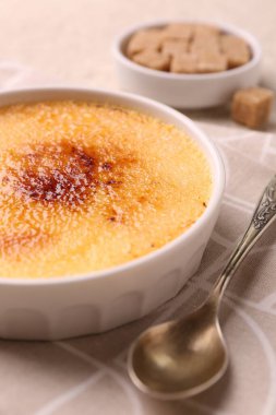 Lezzetli creme brulee kasede ve kaşıkta masada, yakın plan