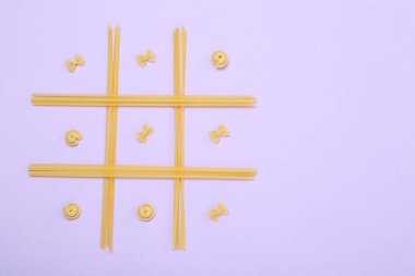 Leylak arkaplanda farklı türde makarna ile yapılan tik tak parmak oyunu, üst görünüm