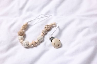 Bebek aksesuarı. Beyaz kumaşta emzik klipsi