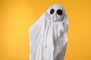 Ürkütücü hayalet. Sarı arka planda beyaz çarşafla kaplanmış kişi
